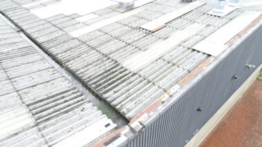Close-up of the old asbestos roof showing its worn-out condition.