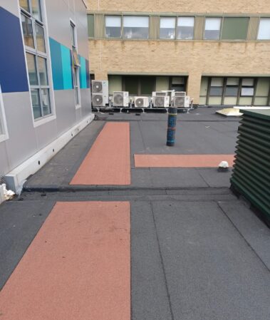 An aerial view of the roof, emphasizing the red demarcated walkway and its contrast against the new roofing material.
