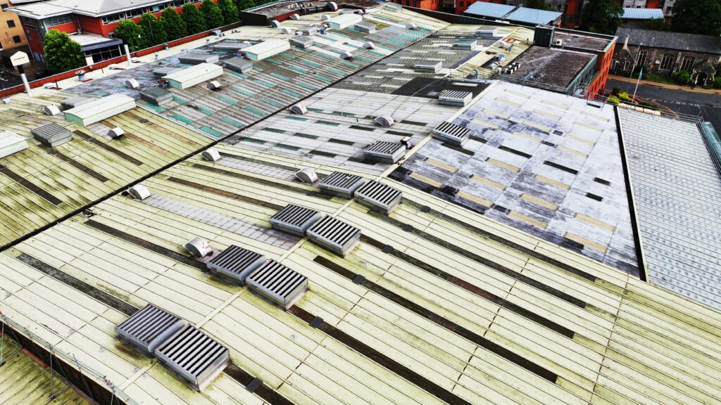 Close-up aerial view of an industrial roof in Norwich with ventilation units and signs of aging.