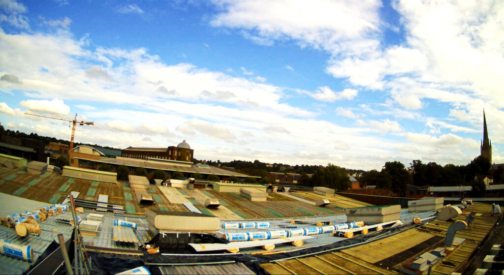 Industrial roof undergoing renovation with a crane in Norwich.